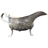 A SILVER SAUCE BOAT WITH REPOUSSE DECORATION, depicting dogs and foliage, on three lion mask paw