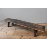 A LATE 18TH/EARLY 19TH CENTURY ELM PIG BENCH, of simplistic rustic form, each end supported by two