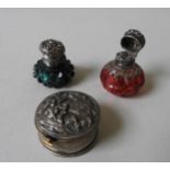 TWO VICTORIAN SILVER MOUNTED SCENT BOTTLES AND A WHITE METAL PILL BOX, the ruby and emerald glass