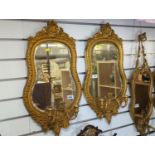 Pair of ornate hour glass shaped gilt framed bevelled mirrors with candle sconces 66cm x 36cm