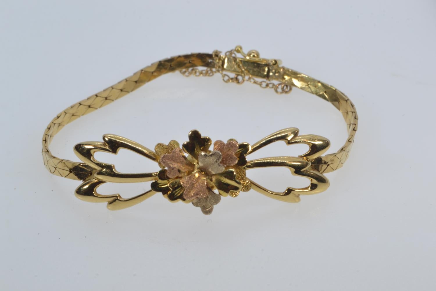 Yellow metal tri-colour bracelet, with an open work floral design to the front, tested positive for 