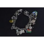 Silver bracelet with padlock clasp with mostly white metal charms, circumference 180mm, gross weight