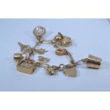 9ct gold charm bracelet with heart-shaped padlock clasp, suspending twelve 9ct gold charms, each lin