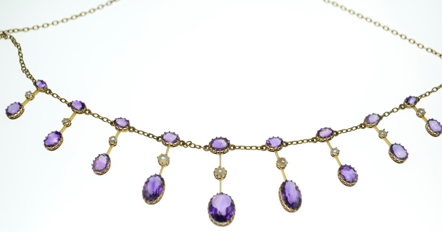 An Edwardian amethyst and half pearl gold fringe necklace, comprising graduating claw-set oval-cut a