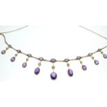 An Edwardian amethyst and half pearl gold fringe necklace, comprising graduating claw-set oval-cut a