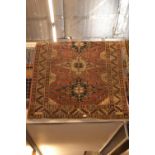 Geometric patterned bordered rug with tones of red, cream and blue, 127 x 160cm