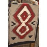 A small Navajo hand woven rug - 'Klagetoh Red' style featuring a grey background with large central