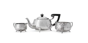 AN ARTS AND CRAFTS HAMMERED SILVER THREE PIECE TEA SERVICE, BARKER BROTHERS