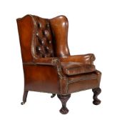 A walnut and leather buttoned wing back armchair in George II style