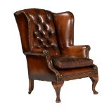 A walnut and leather buttoned wing armchair in George II style