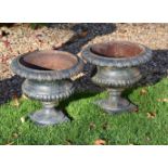 A pair of green painted cast iron garden urns