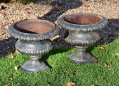 A pair of green painted cast iron garden urns