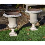 A pair of cream painted cast iron garden urns