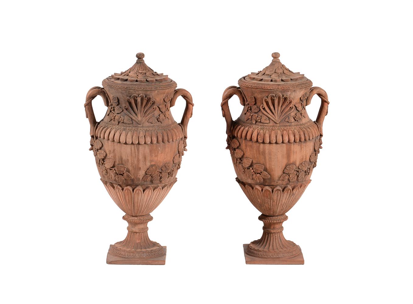 A pair of terracotta twin handled baluster urns and covers, in Italian Baroque taste
