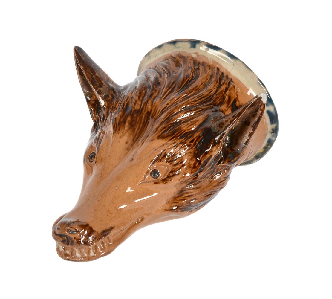 A STAFFORDSHIRE BROWN-GLAZED CREAMWARE FOX MASK STIRRUP CUP