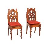 A PAIR OF VICTORIAN CARVED OAK HALL CHAIRS IN GOTHIC TASTE