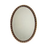 AN OVAL SIMULATED ROSEWOOD WALL MIRROR