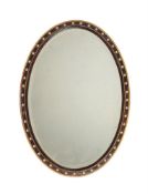 AN OVAL SIMULATED ROSEWOOD WALL MIRROR