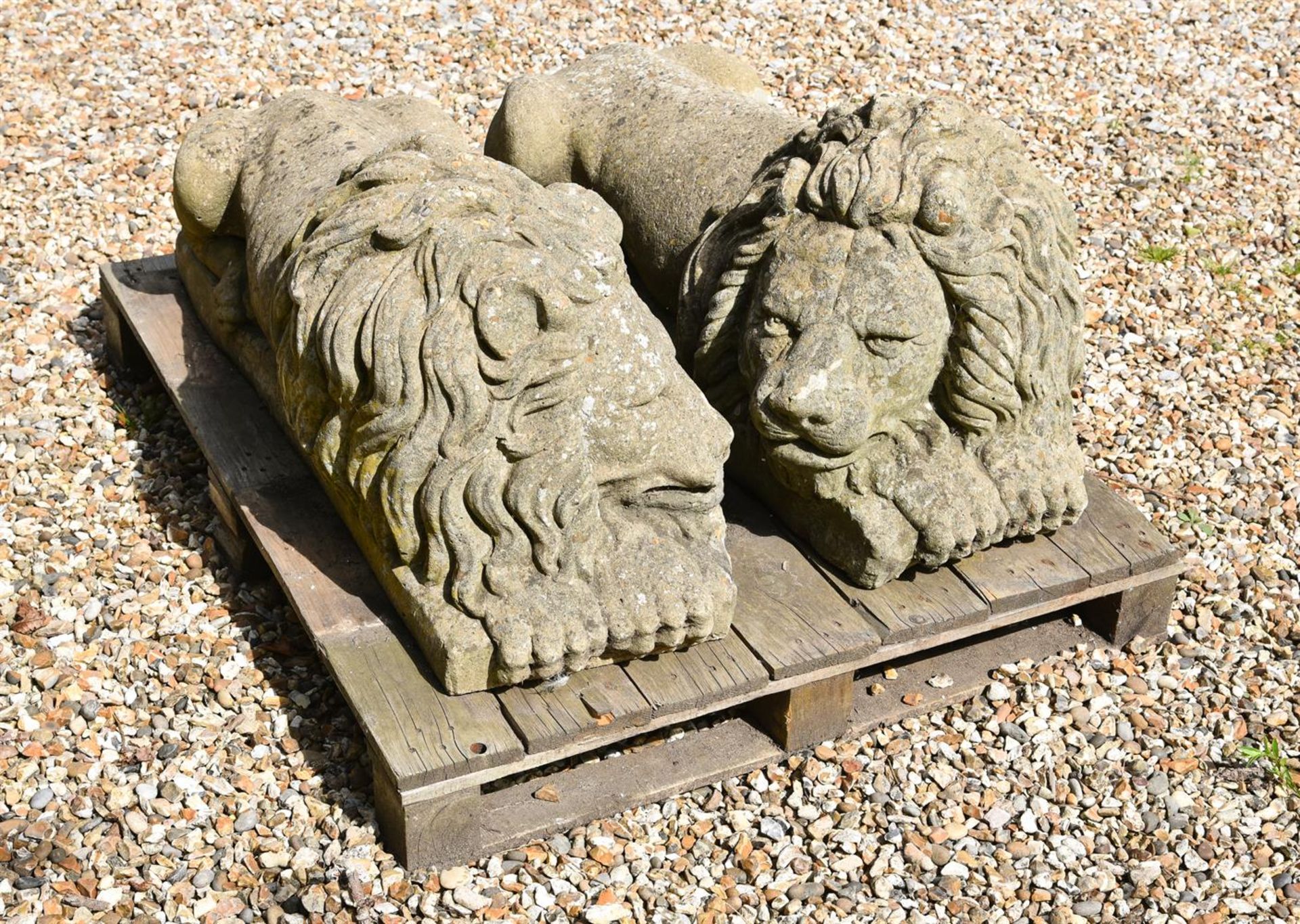 A PAIR OF STONE COMPOSITION RECUMBENT LIONS LOOSELY IN THE MANNER OF ANTONIO CANOVA