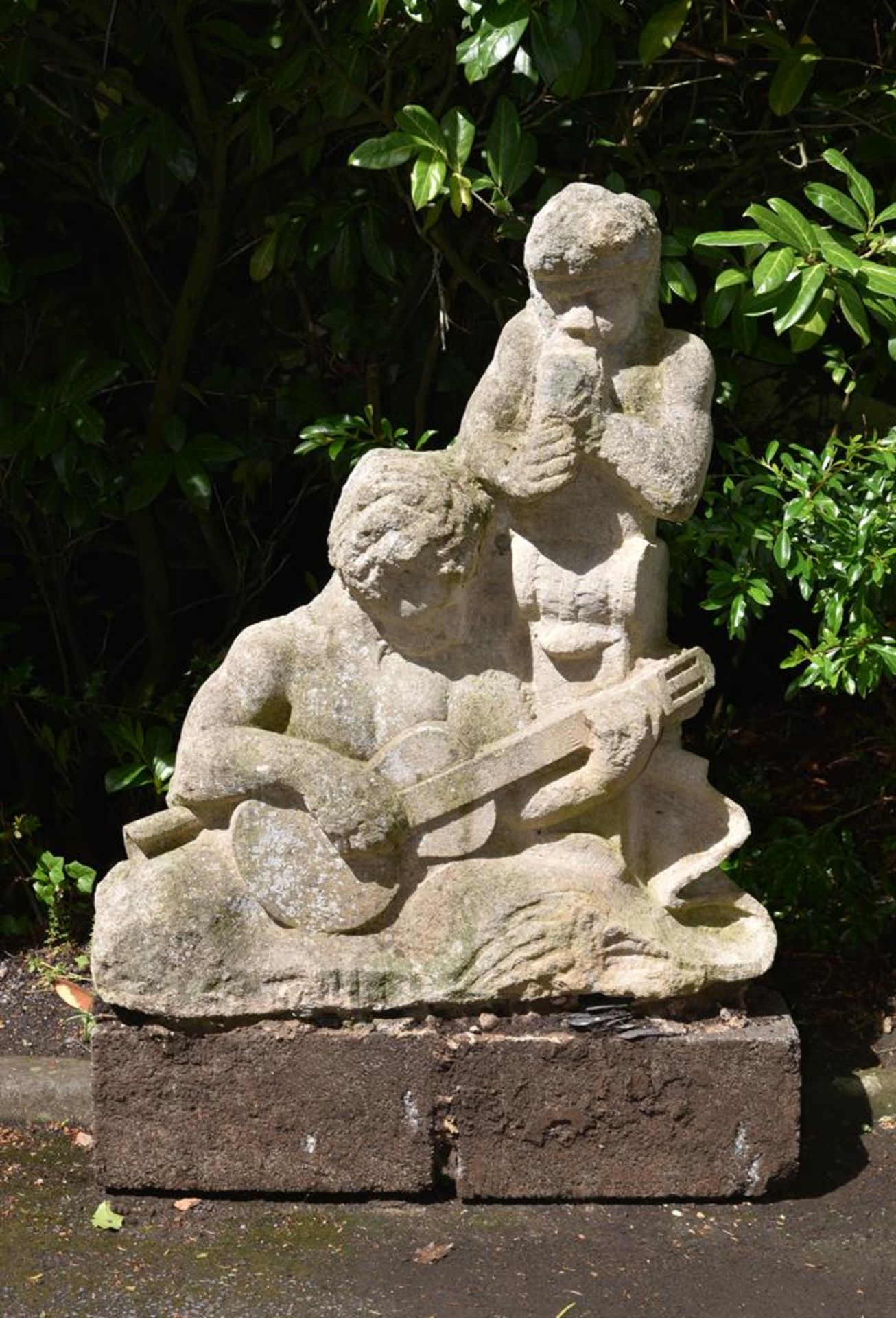 λ SIMON VERITY, A SCULPTED STONE GARDEN SCULPTURE GROUP OF A GUITARIST AND PIPER