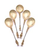 A SET OF FOUR CAST SILVER AND SILVER GILT APOSTLE SPOONS AND A SIFTING SPOON