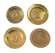A GROUP OF FOUR EMBOSSED BRASS CHARGERS OR ALMS DISHES