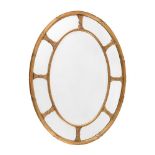 A GILTWOOD AND COMPOSITION OVAL WALL MIRROR IN GEORGE III STYLE