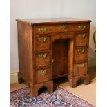 A GEORGE II FIGURED WALNUT AND FEATHER BANDED KNEEHOLE DESK, CIRCA 1730