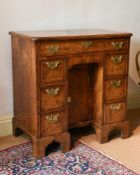 A GEORGE II FIGURED WALNUT AND FEATHER BANDED KNEEHOLE DESK, CIRCA 1730