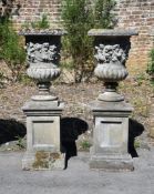 A PAIR OF COMPOSITION STONE VINE PATTERN URNS ON STANDS, IN THE ITALIAN MANNER, MODERN