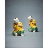 A pair of Chinese biscuit glazed models of seated smiling boys