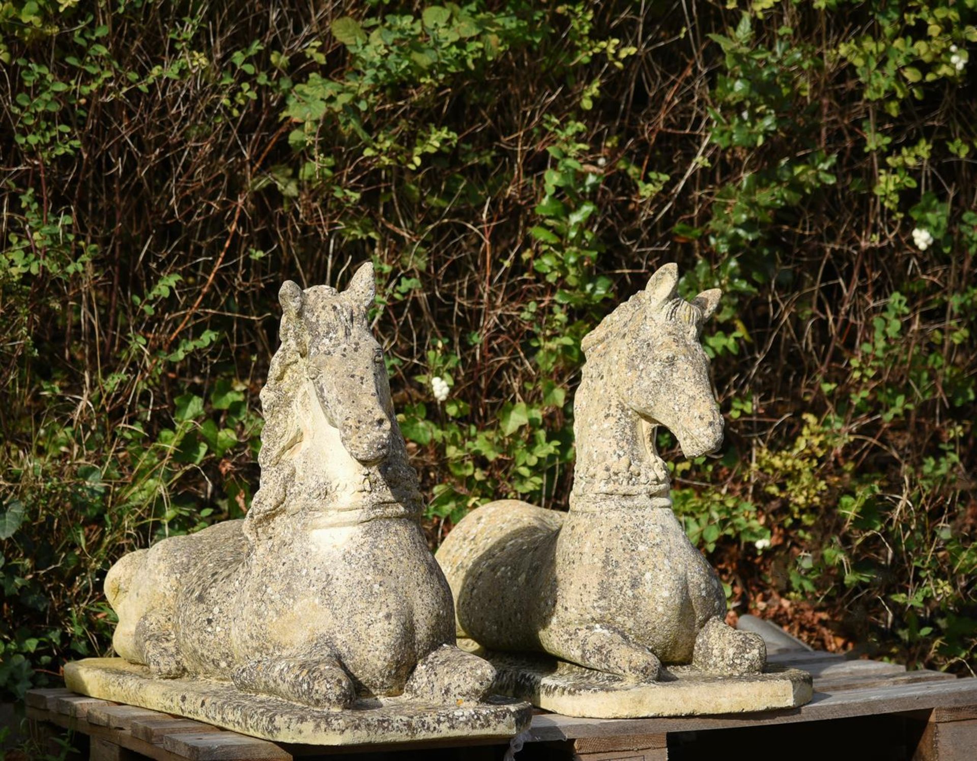 A PAIR OF COMPOSITION STONE RECUMBENT HORSES, 20TH CENTURY