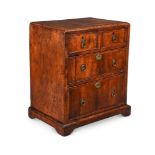 A GEORGE II WALNUT AND FEATHER BANDED MINIATURE CHEST OF DRAWERS, CIRCA 1735