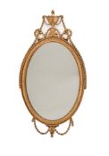 A GILTWOOD AND COMPOSITION OVAL WALL MIRROR IN GEORGE III STYLE