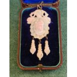 An Edwardian carved coral brooch of shell form with sea serpants, female bust and Perriwinckle drops