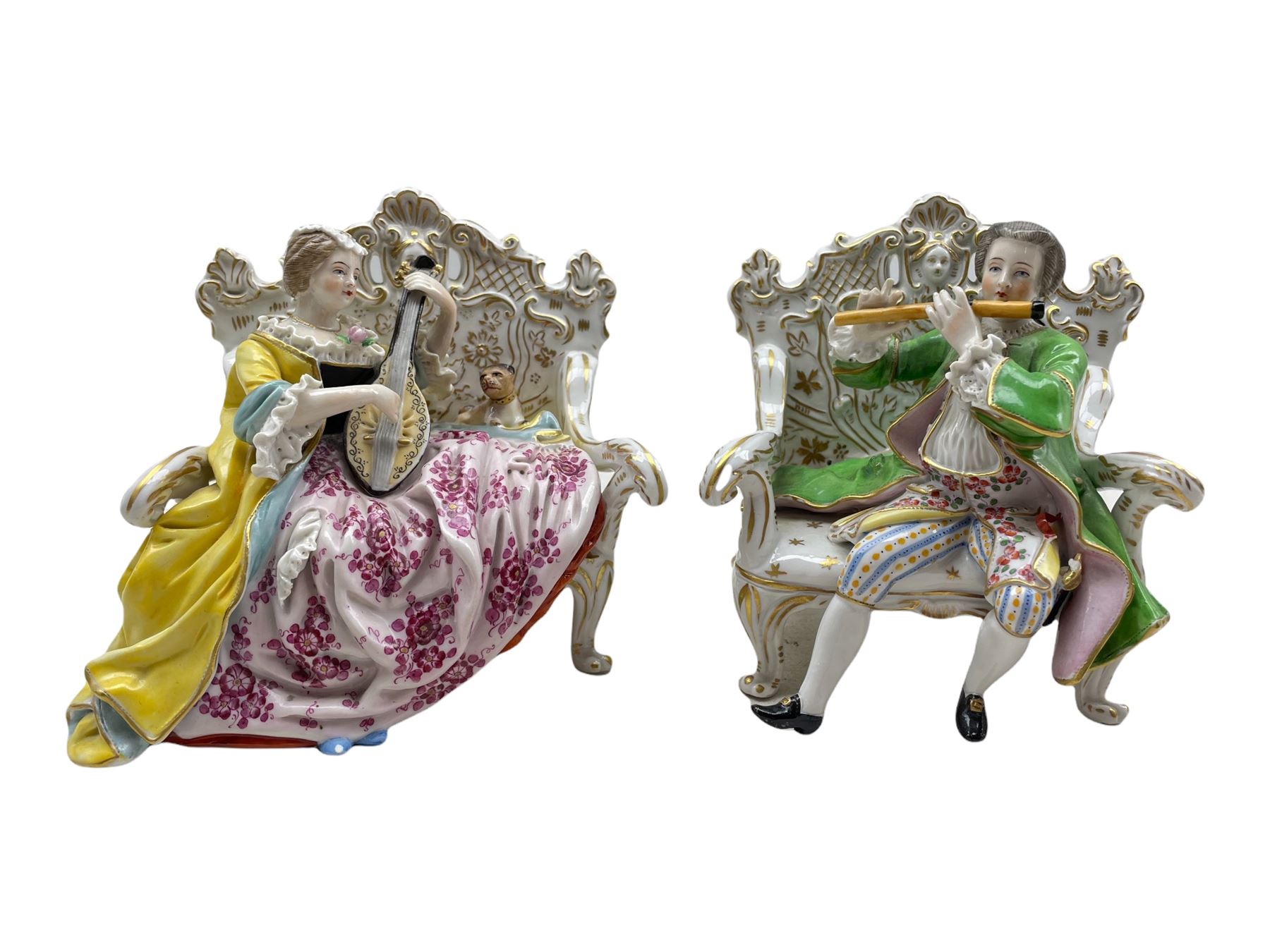 Pair of Hochst porcelain figures modelled as a male and female figure seated on an ornate sofa playi