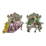 Pair of Hochst porcelain figures modelled as a male and female figure seated on an ornate sofa playi