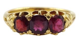 Early 20th century 18ct gold three stone garnet ring with scroll design shoulders