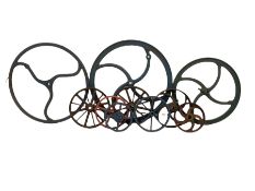 Ten cast iron wheels of various different sizes and colours
