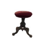 Victorian carved piano stool. the swivel seat upholstered in red fabric over carved column leading i