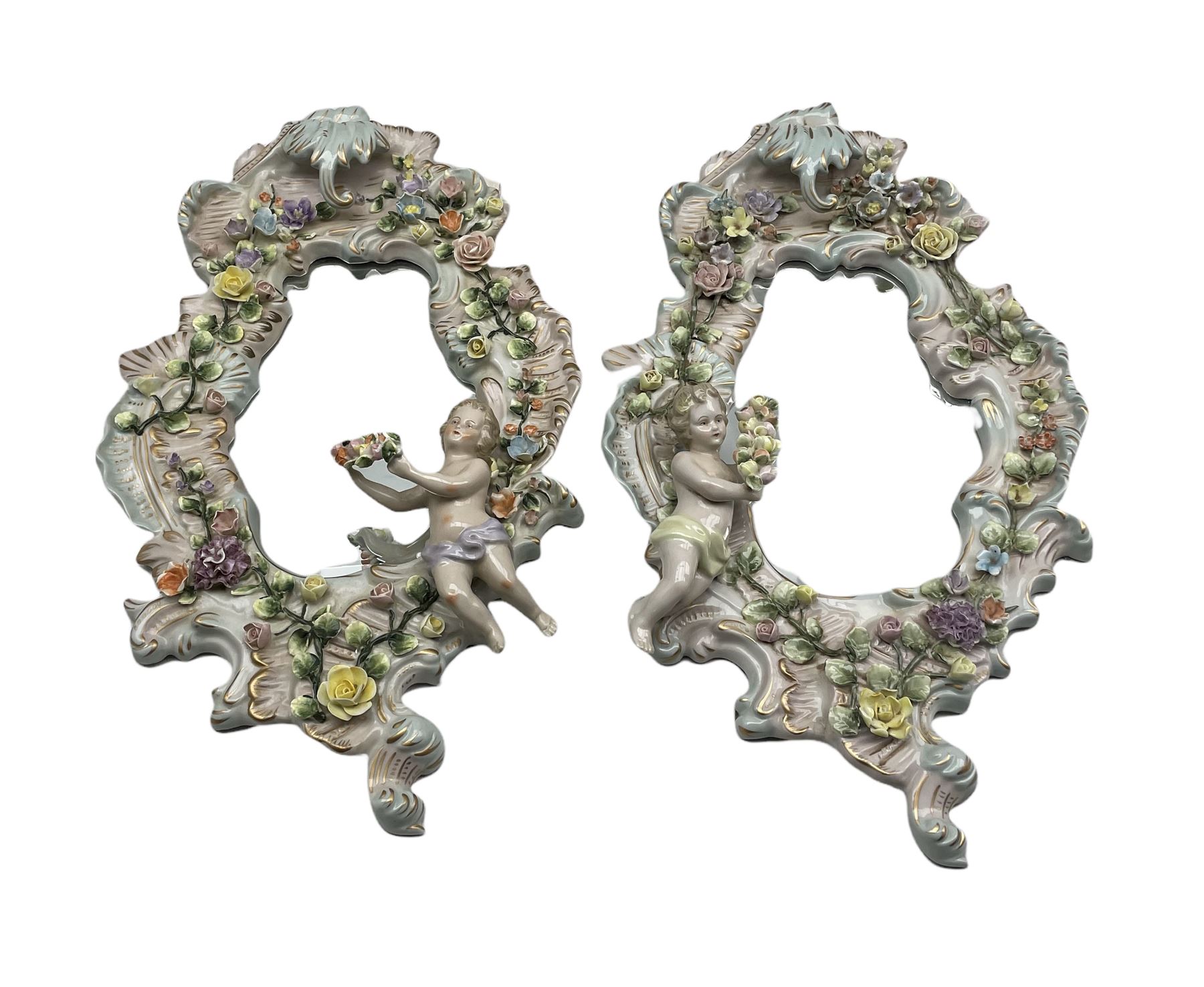 Pair Sitzendorf scroll shaped porcelain wall mirrors applied with flowers and Putti