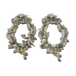 Pair Sitzendorf scroll shaped porcelain wall mirrors applied with flowers and Putti