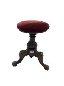 Victorian carved piano stool. the swivel seat upholstered in red fabric over carved column leading i