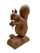 Carved oak model of a Squirrel standing on a branch holding an acorn