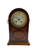 A decorative early 20th century French mantle clock in a round topped mahogany case with inlaid sati