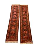 Pair of Persian runner rugs of geometric design on red field with floral border and twin guard strip