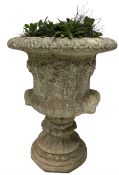 Reconstituted stone garden urn with foliate decoration and bearded masks raised on base with floral