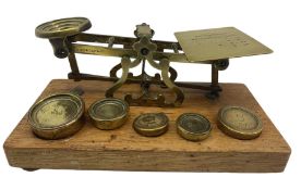 Set of brass postal scales by S Mordan & Co on an oak plinth and five brass weights