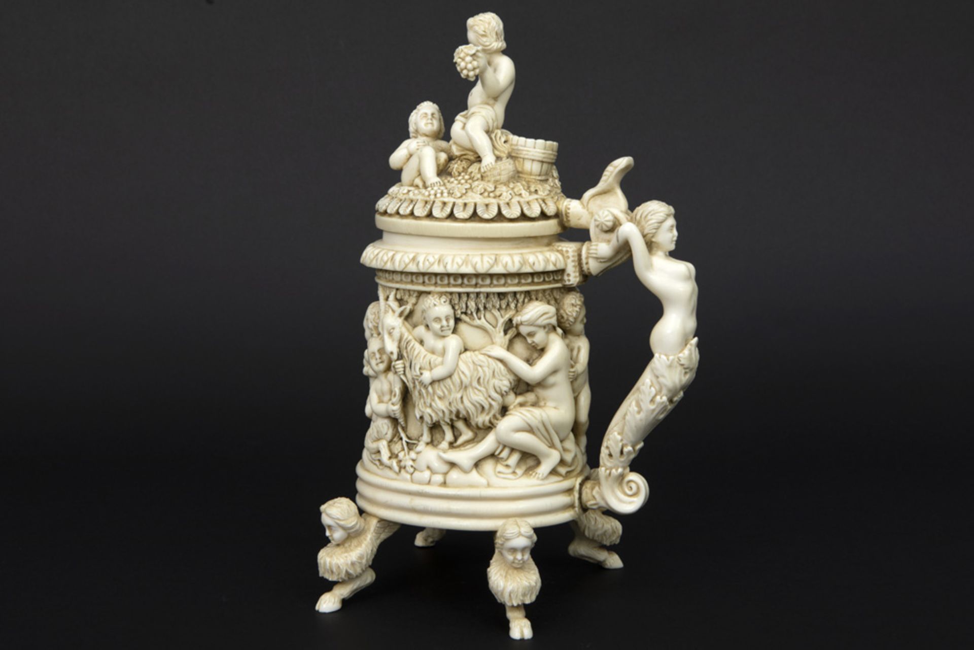 superb 19th Cent. European ivory mug with finely sculpted cupids, two godesses and a ram ||