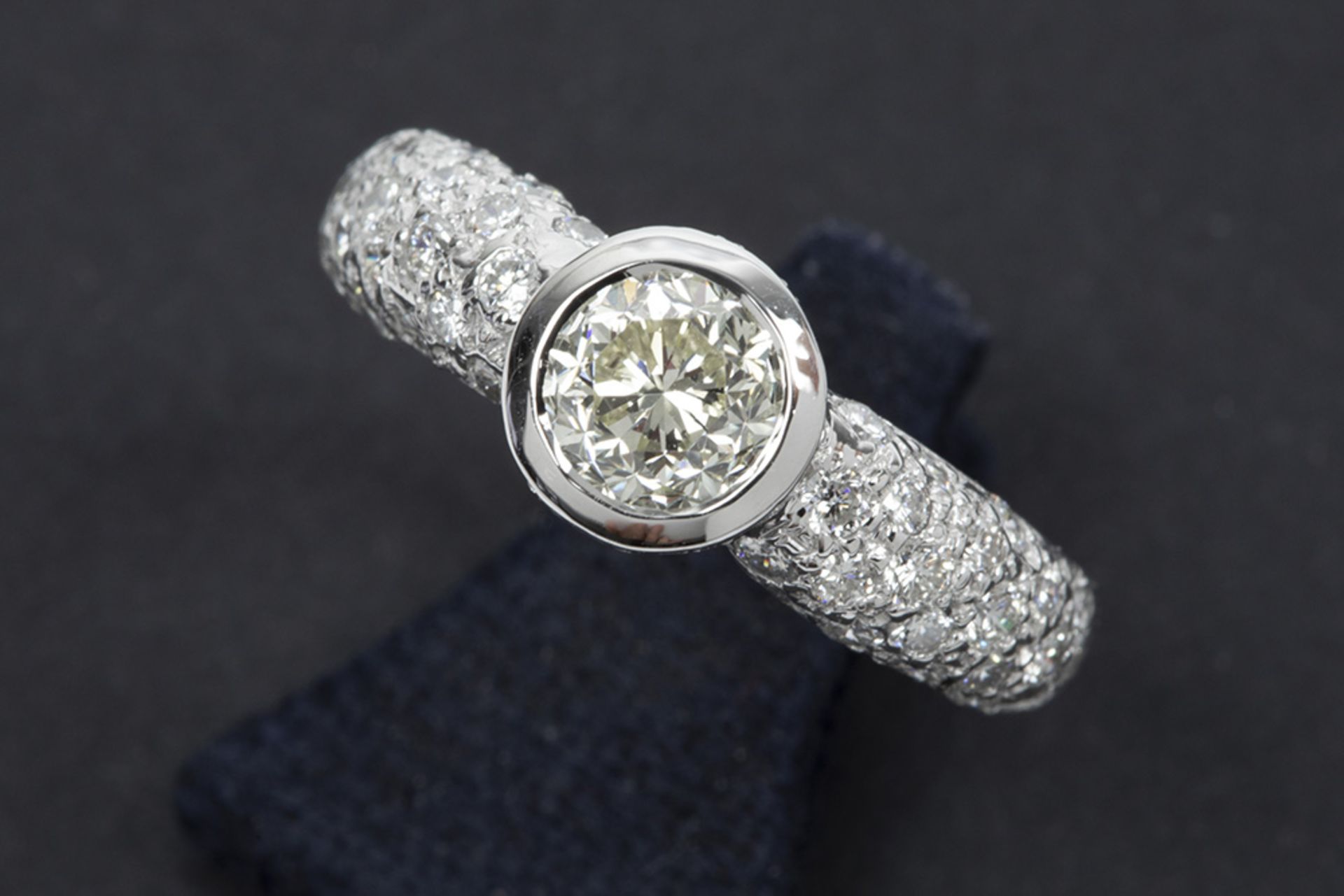 a 1 carat quality brilliant cut diamond set in a ring in white gold (18 carat) with ca 0,70 carat of